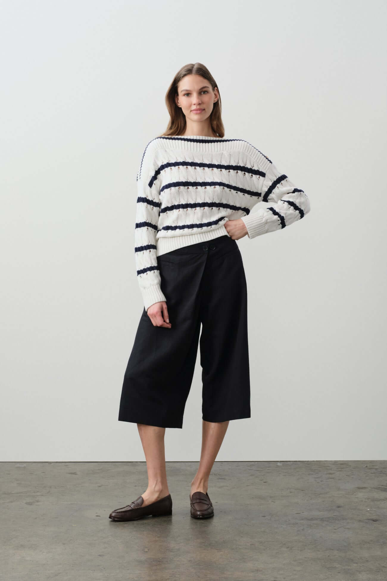 Model wearing a stylish striped sweater from the Sweaters collection in a modern setting.