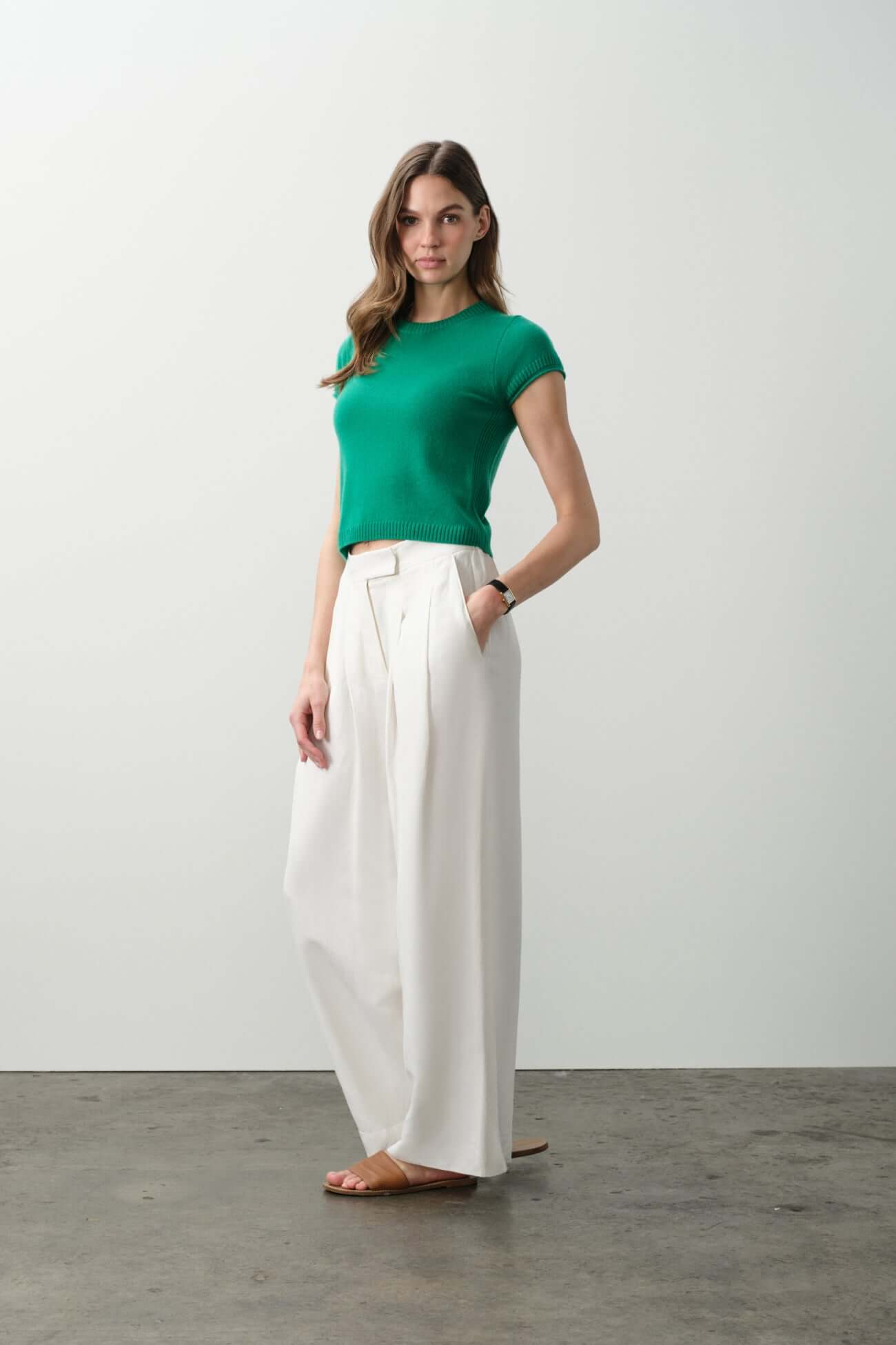 Model wearing a green top paired with wide white pants, showcasing stylish Tops from the collection.