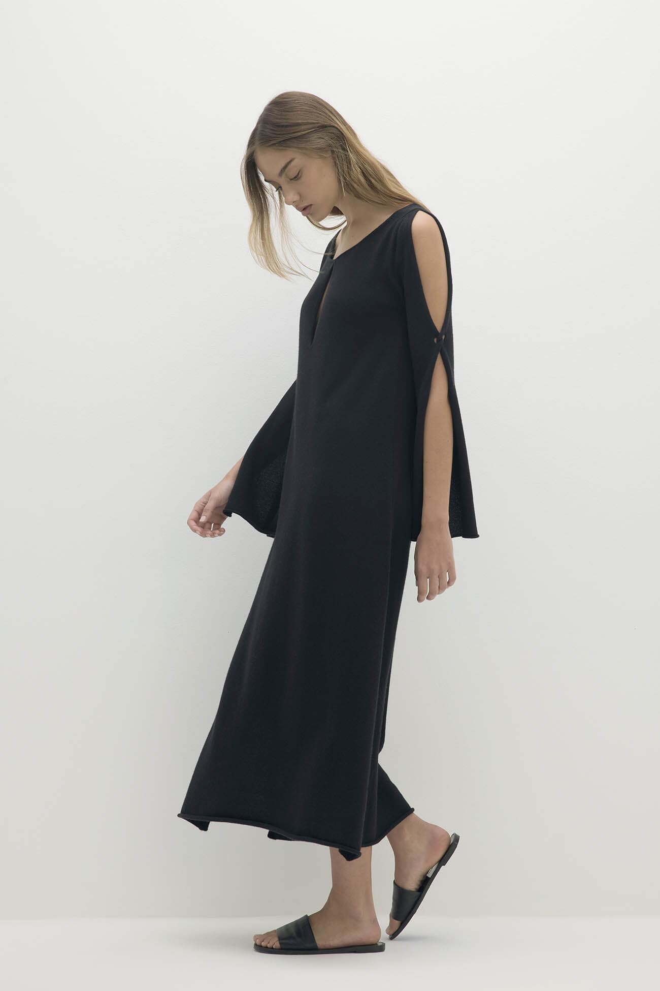 A woman wearing a stylish black dress with cut-out sleeves, showcasing elegant design in the Dresses collection.